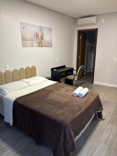 a bedroom with a large bed and a desk at Casa Joinville in Joinville