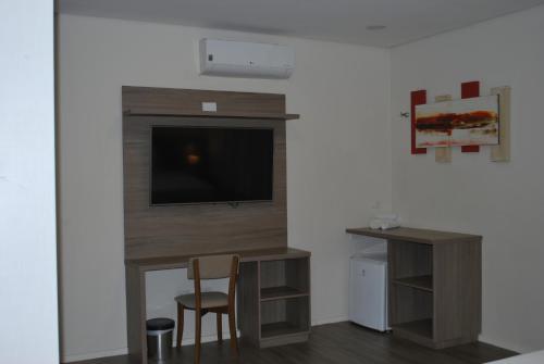 a living room with a tv and a desk with a chair at Sumaré Park Hotel in Sumaré