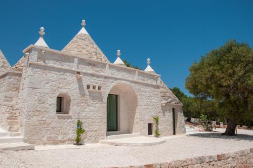 an old stone building with a tree in the background at Trulli Moranera in Cisternino