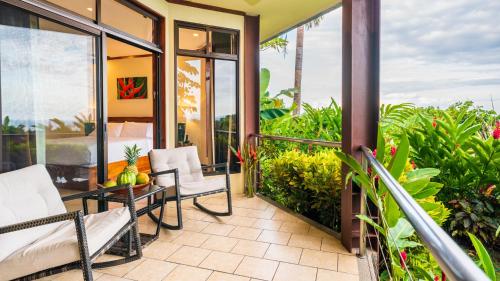 a balcony with white chairs and a table at Tulemar in Manuel Antonio