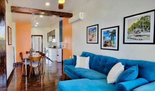 a living room with a blue couch and a table at 360 Suites - Seaside 6Bedroom Retreat in Caye Caulker