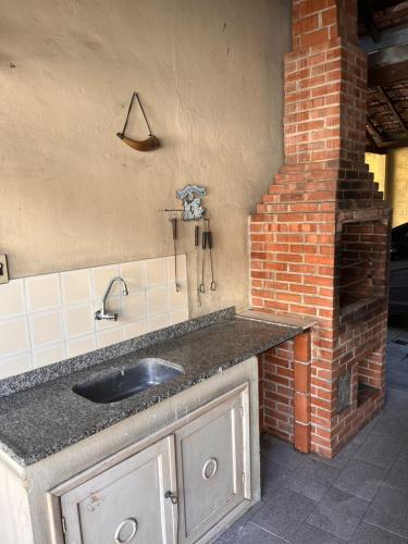 a kitchen with a sink and a brick wall at Keller Reservas in Resende