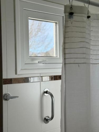 a white door with a window in a bathroom at La Calala Aparts in Esquel