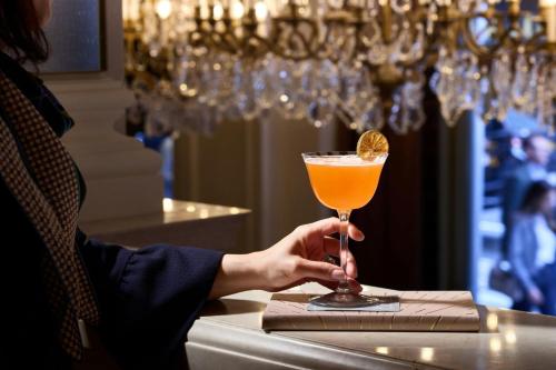 a person is holding a drink in a glass at The St. Regis New York in New York