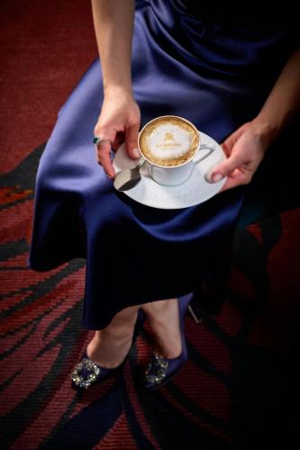 a person holding a cup of coffee on a plate at The St. Regis New York in New York