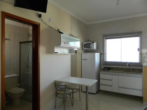 a small kitchen with a table and a white refrigerator at Áries Apart Hotel in Bauru