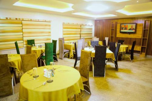 a dining room with yellow tables and chairs at Ascot Tulip Hotel in Enugu
