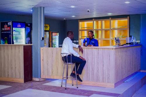 two men sitting at a bar in a restaurant at Ascot Tulip Hotel in Enugu