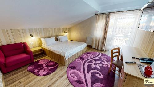 a hotel room with a bed and a red chair at Pensiunea Bianca in Botoşani