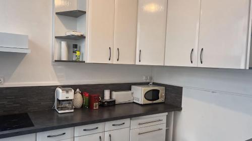 a kitchen with white cabinets and a microwave at Maison de ville cosy Saumur avec Cour A 5 min à pied centre in Saumur