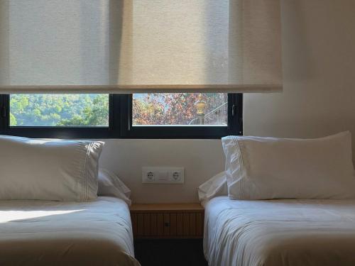 two beds in a room with a window at El Balcón de Potes in Potes