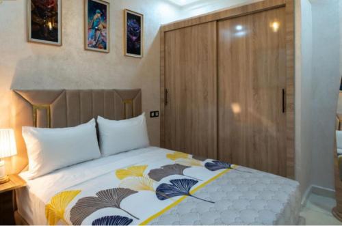 a bedroom with a bed and a wooden cabinet at Riad Bollywood- International in Benguerir