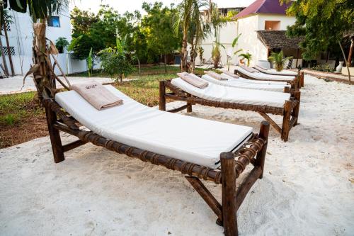 a row of wooden beds sitting in the sand at Hostel 197 in Nungwi