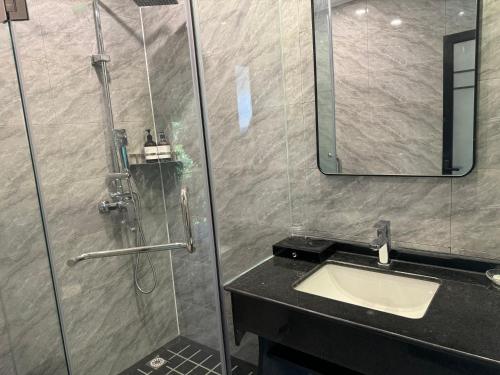 a bathroom with a shower with a sink and a mirror at 兰亭山庄 in Kaôh Rŭng (5)