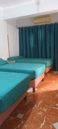 three beds in a room with blue curtains at Villa Rose-Luxor in Luxor