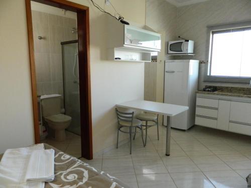 a small kitchen with a table and a refrigerator at Áries Apart Hotel in Bauru