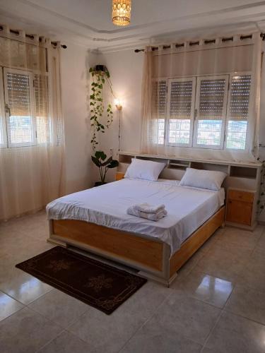 a bedroom with a large bed with white sheets and windows at Karyat arkman nador in Nador