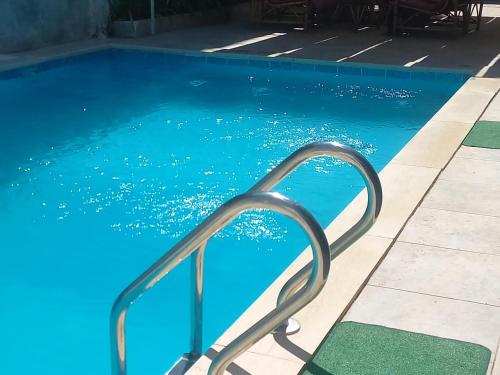 a blue swimming pool with a metal hand rail at Villa Rose-Luxor in Luxor