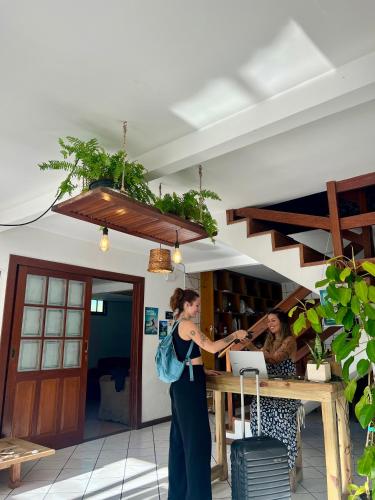 a woman standing in front of a counter with her luggage at Nômades Beach - Adventure Hostels in Florianópolis