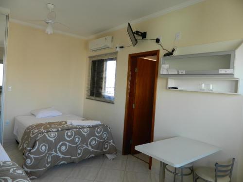 a room with a bed and a table in it at Áries Apart Hotel in Bauru