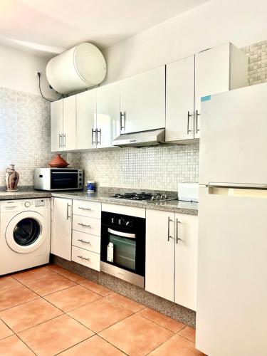 a kitchen with white cabinets and a washer and dryer at Beautiful apartment with pool and sea horizon view in Fnidek