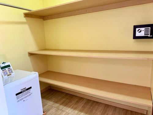 a laundry room with wooden shelves and a refrigerator at Hotel Fazenda Vale Alvorada in Cascavel