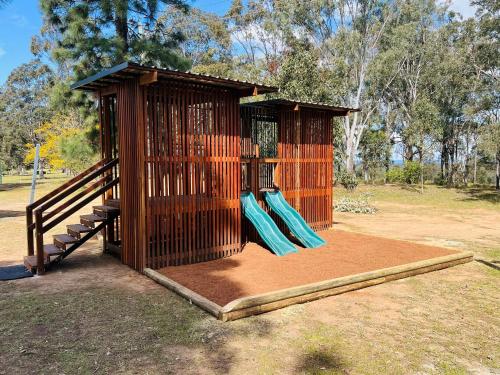 a playground with a wooden play structure with blue slides at Palmers Lane Estate Hunter Valley in Pokolbin