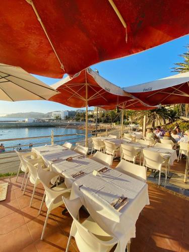 a group of tables and chairs with umbrellas on a deck at BEACH Arguineguin FIRST LINE 8 studio CHG FAMILY HOTEL in Arguineguín