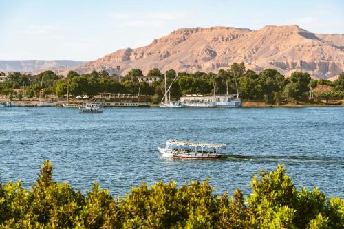 a boat on the water with mountains in the background at Bab Al Shams Palace in Luxor