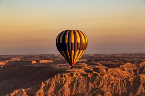 a hot air balloon flying over the desert at Bab Al Shams Palace in Luxor
