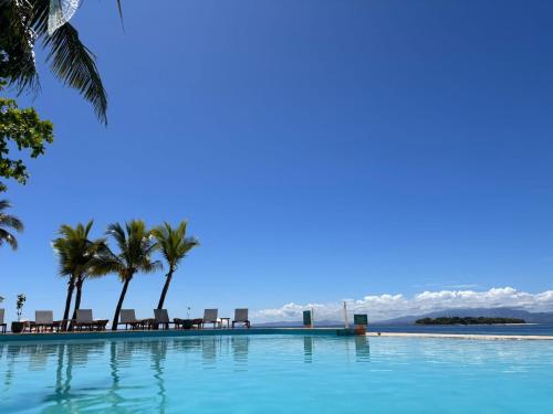 a swimming pool with chairs and palm trees and the ocean at Beachcomber Island Resort in Beachcomber Island