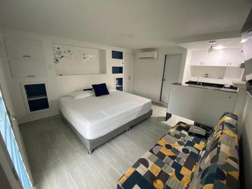 a bedroom with a large white bed and a kitchen at La Casa Blanca Hotel in Buenaventura