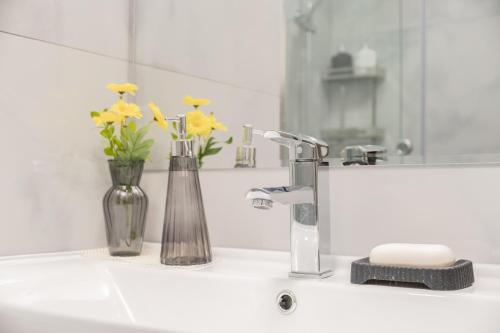 a bathroom sink with a vase of flowers and a mirror at Nest One Luxe, Элитные апартаменты с балконом и видом на фонтан Tashkent City Park 077 in Tashkent