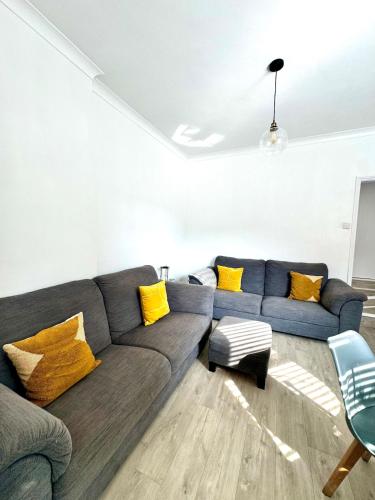 a living room with a blue couch and yellow pillows at Charming 2BR Victorian Flat in Bexhill-on-Sea in Bexhill