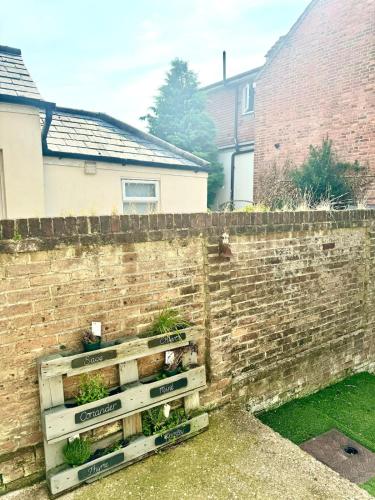 a brick wall with three wooden crates with plants in them at Charming 2BR Victorian Flat in Bexhill-on-Sea in Bexhill
