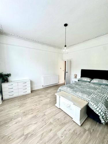 a white bedroom with a bed and a wooden floor at Charming 2BR Victorian Flat in Bexhill-on-Sea in Bexhill
