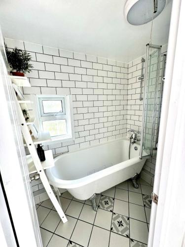a white bathroom with a tub and a window at Charming 2BR Victorian Flat in Bexhill-on-Sea in Bexhill