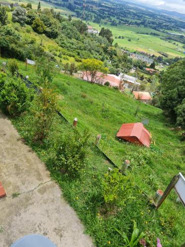 a grassy hill with a red house on it at Chalet Montaña Tenjo Mirador in Tenjo