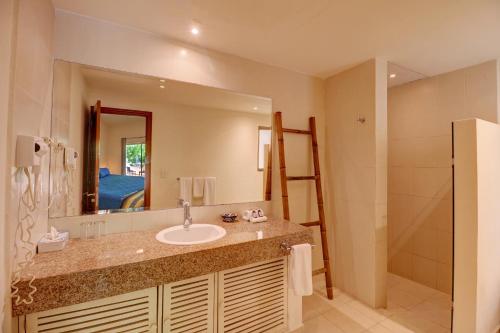 a bathroom with a sink and a mirror and a shower at Palmar del Sol by Riviera Maya Suites in Playa del Carmen