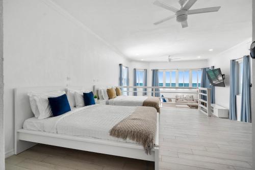 a white bedroom with a large bed with blue pillows at House Jorja in Nassau