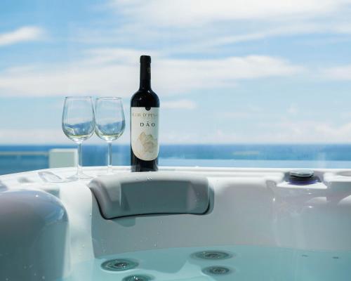 a bottle of wine sitting on a table with two glasses at Beira Da Rocha in Ponta Delgada