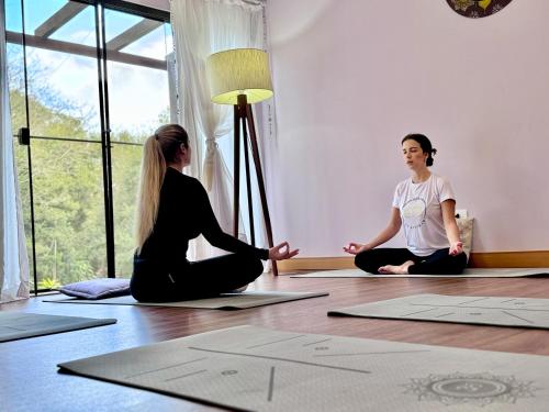 two women sitting on the floor in a yoga class at Hotel Fazenda Vale Alvorada in Cascavel