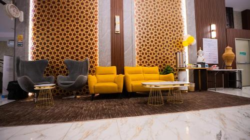 a lobby with a yellow couch and three chairs at فندق يقين مكة in Makkah