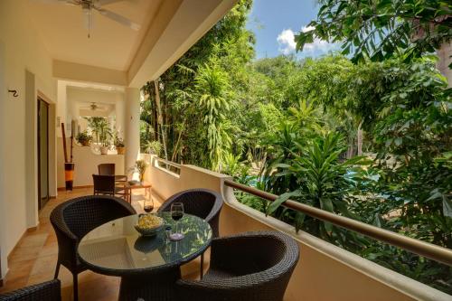 a balcony with a table and chairs and trees at Palmar del Sol by Riviera Maya Suites in Playa del Carmen