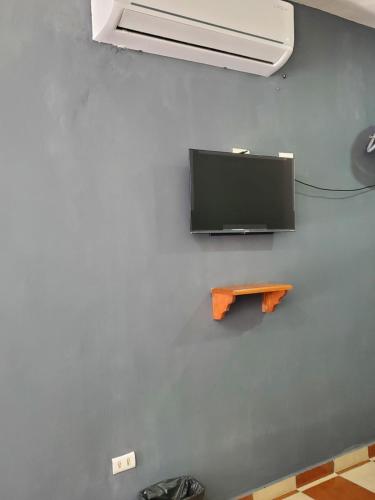 a tv on a blue wall with a wooden shelf at Casa Camino Real, Habitación 1, Baño privado, Cafetera Escritorio in Ciudad Valles