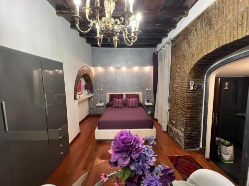 a bedroom with a bed with purple sheets and a chandelier at Domus31 - Luxury House in Trastevere in Rome