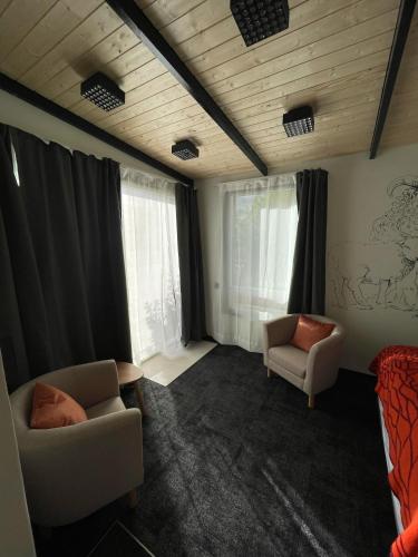 a room with two chairs and a bed and windows at Amma Jóna rooms in Ásólfsskáli