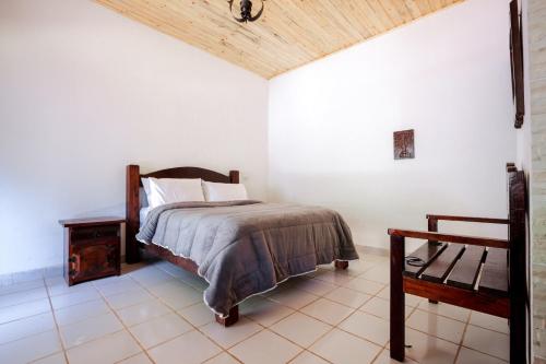 a bedroom with a bed and a wooden ceiling at Sítio Portal - Chalés com cachoeira 20 min Monte Verde in Monte Verde