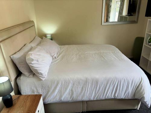 a bedroom with a bed with white sheets and pillows at High class accommodations 10 in Little Hulton