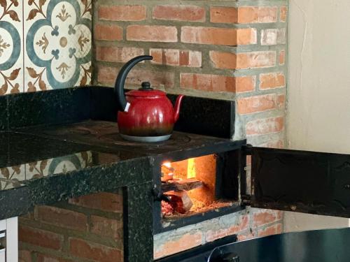 a red tea kettle on top of a brick oven at Hotel Fazenda Vale Alvorada in Cascavel